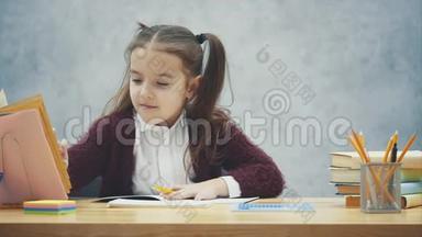 一个聪明的女学生坐在桌子旁写作业。 在此搜索书中的页面