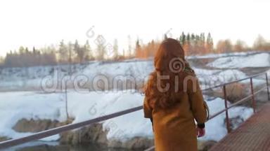 一位年轻的红发女子在<strong>日</strong>出时沿着桥过一条小河。