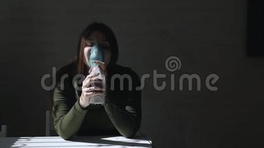 使用雾化器和吸入器进行治疗。 年轻女子坐在桌子旁，用面罩在黑暗中吸入吸入器