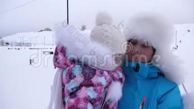 在冬天，妈妈抱着她的小女儿在雪道上散步。 家长与孩子在公园散步