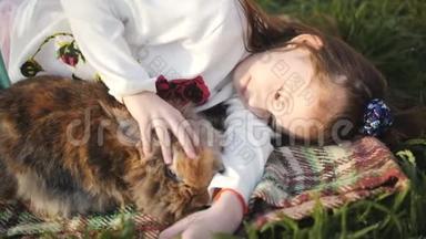 小女孩躺在绿草上拥抱一只棕色的兔子。 小女孩和棕色兔子躺在绿色的草坪上，<strong>还有</strong>一只