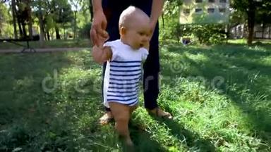 小宝宝学会走路.. 第一步。 父母在教孩子在草地上迈出第一步