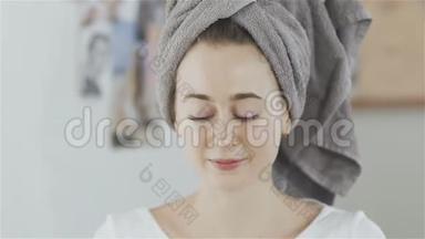 女人头上戴着毛巾，脸上涂着油<strong>润肤露</strong>，看着镜头