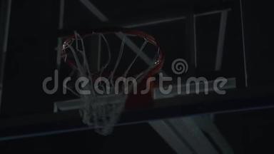 特写职业篮球运动员在黑暗篮球场篮球比赛中扣篮的形象..