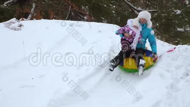 妈妈和女儿在<strong>冬天</strong>的雪碟上从高高的雪山上翻滚，笑了起来。 快乐的母亲和<strong>小孩</strong>子