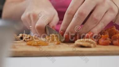 一位年轻的家庭主妇用一把刀在切割板上切割干果葡萄干. 健康饮食观念
