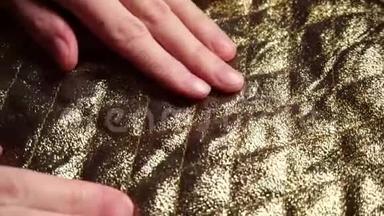 女人触摸一个光滑，金色尼龙涤纶织物在一<strong>家纺</strong>织品商店。