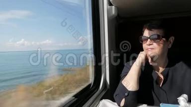 一位身穿黑色衬衫、戴墨镜、坐在<strong>火车车厢</strong>窗户附近的老妇人