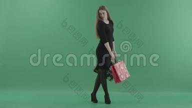 美丽快乐的女人穿着黑色的小裙子，摆姿势，用购物袋旋转。 她站在工作室里