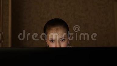 一个年轻的女孩晚上在房间里看电脑屏幕，眼睛很累。 疲惫的少女看着屏幕