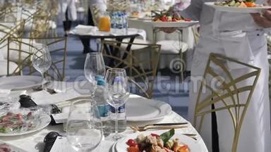 自助餐厅和酒店。 饮食服务服务员在婚礼或研讨会上把盘子和盘子放在客人的桌子上