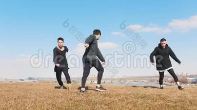 三个年轻人在草地上同步表演杂技表演