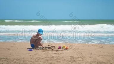 一个小男孩正在大海上的沙子里玩耍，小腿和手指，大海的背景是黄沙和碧水