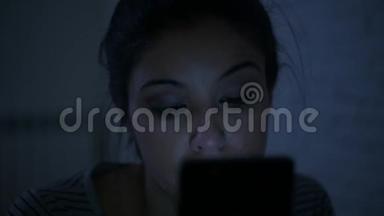 一个30多岁的西班牙裔年轻女子，躺在床上，<strong>深夜</strong>用手机<strong>看</strong>着，侧着侧着的平底锅