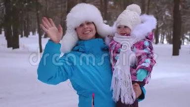 <strong>妈妈抱</strong>着她的小女儿在冬天下雪公园，笑着挥手。 圣诞周末。 <strong>妈妈</strong>带着孩子散步