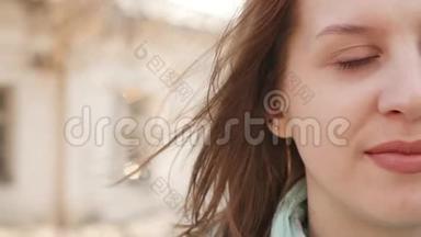 一位年轻女子站在风中的特写肖像。 <strong>春风</strong>吹着女孩`头发。 慢动作