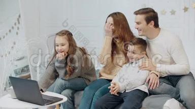 微笑的<strong>家人一起</strong>在客厅的笔记本电脑上<strong>看</strong>视频。