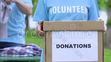 女志愿者手持捐款箱，人们整理衣物，<strong>人道主义援助</strong>