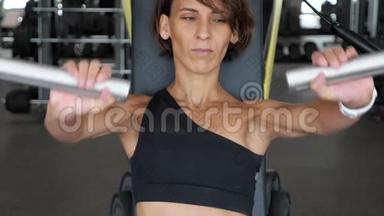 运动的女人正在训练机器上练习手臂肌肉。