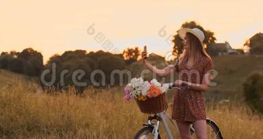 一个漂亮可爱的女孩在阳光明媚的<strong>日</strong>子里，在公园里，在自行车旁边用智能<strong>手机</strong>和手掌。 一个漂亮的女孩