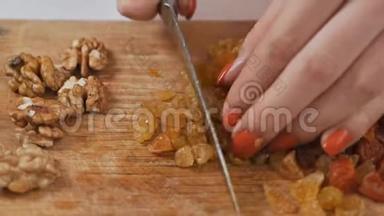 一位年轻的家庭主妇用一把刀在切割板上切割干果葡萄干. 健康饮食观念