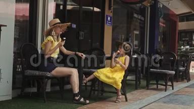 母亲和女儿在夏日的街头咖啡馆吃冰淇淋