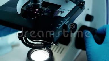双手在实验室用显微镜研究生物<strong>化学材料</strong>。