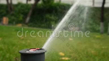 绿化草坪草浇水时的塑料喷雾器.. 花园洒水器在草地上工作。 慢动作