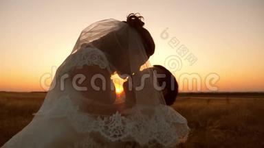 新娘和新郎在日落时亲吻和拥抱。 晚上男女情人之间温柔的吻