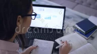 在电子教育期间，学生女孩用<strong>笔记本</strong>画一个图表，坐在一张桌子上，在咖啡馆里放着书和<strong>笔记本</strong>电脑