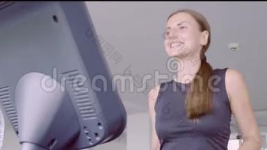 快乐微笑的女人在健身中心的健身房跑步机上跑步。