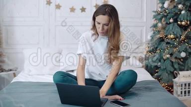 <strong>专心</strong>致志的女人坐在圣诞装饰的房间里拿着电脑。