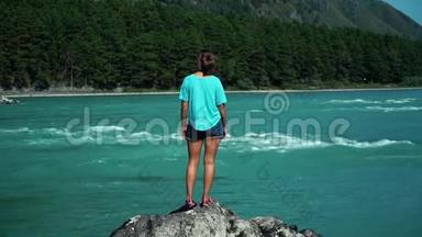 年轻女子站在快速<strong>山河</strong>旁的一件<strong>蓝色</strong>t恤上，看着江流.. 背面