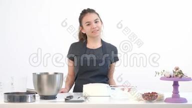 漂亮的黑发<strong>女孩</strong>糕点厨师在<strong>围裙</strong>鞭打奶油蛋糕在一个金属碗。