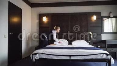 女佣铺了一张<strong>双人床</strong>，在一间舒适的小旅馆房间里把枕头伸直。