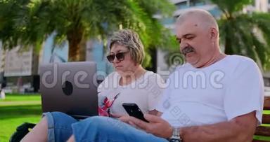 今年夏天，在一个<strong>现代化</strong>的城市里，快乐的老夫妇坐在长凳上，手提电脑放在摩天大楼的<strong>背景</strong>上