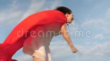 滑稽的超级英雄女孩穿着红色<strong>斗篷</strong>跑着笑，<strong>斗篷</strong>在风中飘扬。 开朗的年轻女人扮演超级英雄