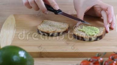 做鳄梨吐司。 女人把鳄梨涂在烤三明治面包上。 顶部视图