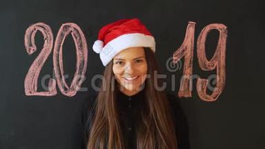 一个戴着圣诞老人`帽子、戴着<strong>黑色石板</strong>墙的快乐女孩的肖像。 新年快乐！