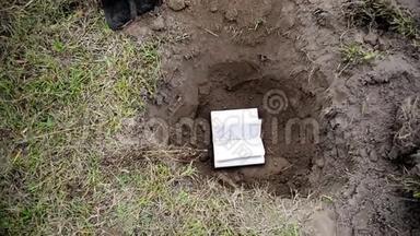 一个手里拿着铲子的人把书埋在地上。 销毁书籍。