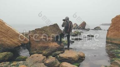 年轻摄影师用数码单反相机拍摄海洋悬崖