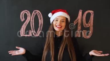 一个戴着圣诞老人`帽子、戴着<strong>黑色石板</strong>墙的快乐女孩的肖像。 新年快乐！