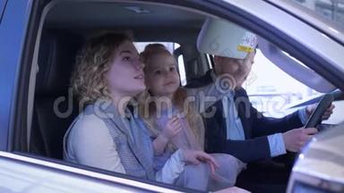 家庭接送购买，年轻顾客家庭带着女孩子仔细考虑汽车内饰坐在沙龙内