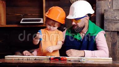 孩子，孩子忙着戴防护头盔，学习用螺丝刀和爸爸拧螺丝。 车间和杂工