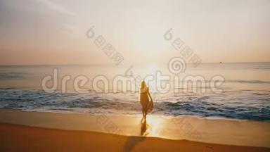 史诗般的<strong>剪影</strong>拍摄的年轻快乐的女人看着令人惊叹的日落田园般的<strong>金色</strong>海洋海滩与银波。
