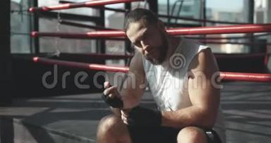 拳击手在雾蒙蒙的健身房锻炼后，坐在拳击场边缘沉思