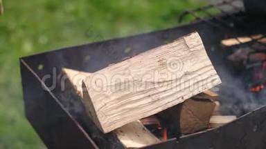 男人在烤架里扔几根木头，<strong>点燃</strong>小火，下午在街上