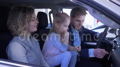 家庭<strong>购车</strong>，带着小女儿的一对微笑的夫妇，一边挥舞着钥匙，一边竖起大拇指，一边看着家庭汽车