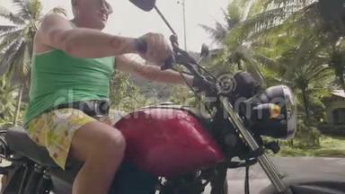 在热带地区骑摩托车的老人。 戴墨镜的老人骑着绿掌的摩托车