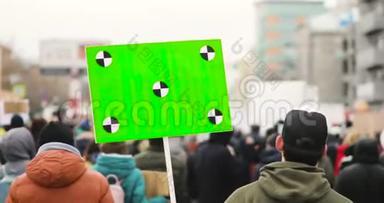 男人拿着绿色屏幕的大<strong>海报</strong>，在城<strong>市集</strong>会上和人群一起走在街上，后景。